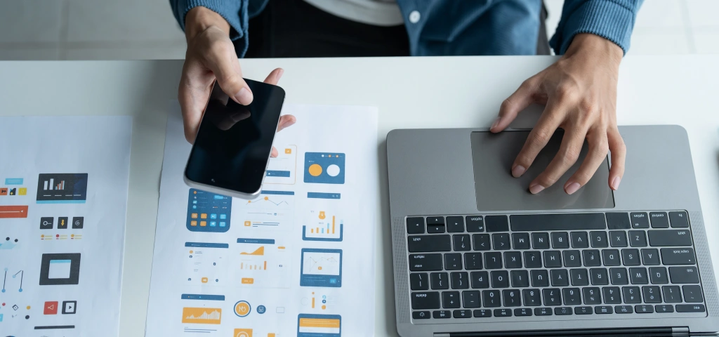 Wireframes impresos junto a un portátil durante la planificación de un proyecto web