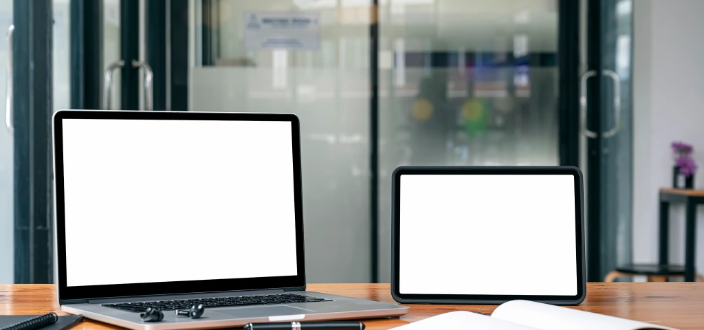 Portátil y tablet con pantallas en blanco sobre una mesa de oficina moderna